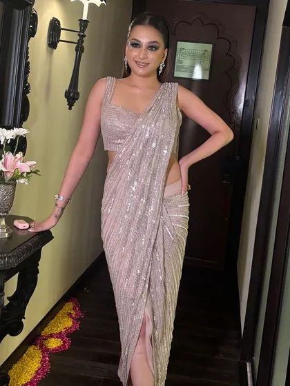 A full-length view of the modern cocktail look. The sleek hair complements the draped silhouette of her saree-gown perfectly.