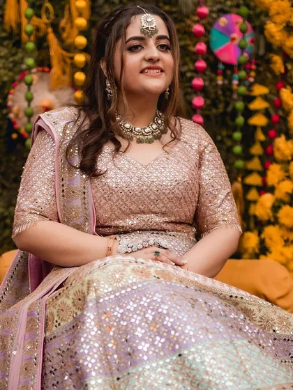 A beautiful solo portrait of the bride during her Kashmiri 'Saath Mainz' ceremony. Her expression is serene and happy, and the mirror-work on her lehenga catches the light beautifully.