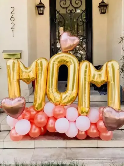 A 'MOM' foil balloon setup with a pink and rose gold balloon base, perfect for a Mother's Day surprise.