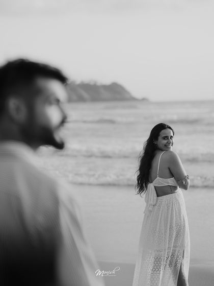 A beautiful black and white portrait from a Goa pre-wedding shoot, capturing a candid glance on the beach.