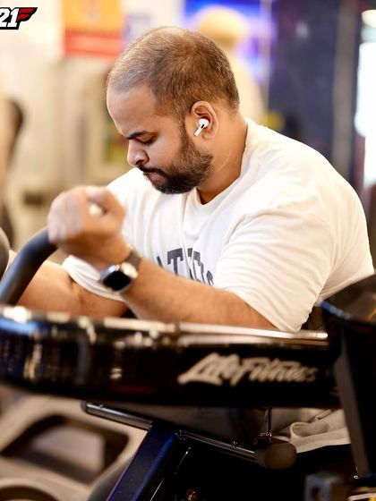 Intense focus during a machine preacher curl. Using machines allows for maximum isolation of the bicep, helping to build a strong mind-muscle connection and a better peak.