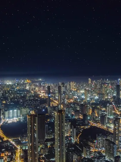 A wide aerial view of Mumbai at night, where the city's glow is so bright it rivals the starry sky above. This shot emphasizes the sheer scale and density of the urban landscape, a city that truly never sleeps.