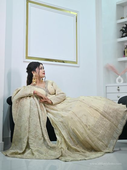 Another angle of the model reclining in the ivory anarkali, offering a full view of the outfit's elegant drape.