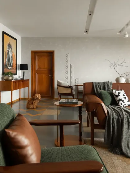This living room blends modern comfort with Indian heritage. The flooring is a detailed pattern of Kota stone and Jaisalmer marble, while the furniture combines clean lines with warm materials like leather and dark wood.