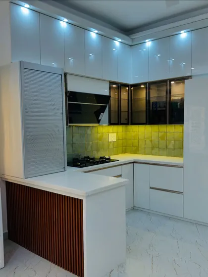 This is the final look of a kitchen where the client wanted a bright, luxurious feel. We used high-gloss white laminate for the cabinets, a beautiful green tiled backsplash, and a functional breakfast counter with a fluted wood panel. The space is now open, airy, and perfect for the family.