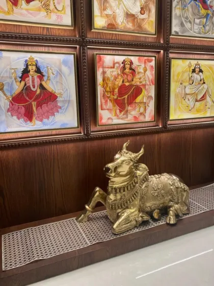 A close-up of a spiritual corner in a home, featuring a gallery wall of goddesses and a brass Nandi statue. This arrangement creates a sacred space for reflection and prayer.