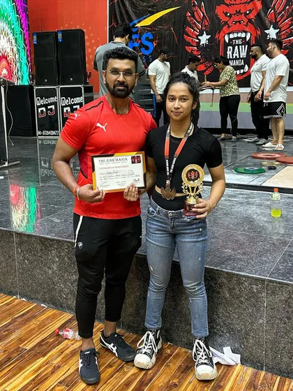 Priyanka standing with her coach after her gold medal win. This picture represents the partnership between a dedicated athlete and an expert trainer, which is the foundation of success.
