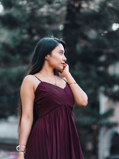 An elegant and graceful portrait in a flowing maroon dress. The soft, diffused light of the outdoors creates a dreamy and romantic mood.