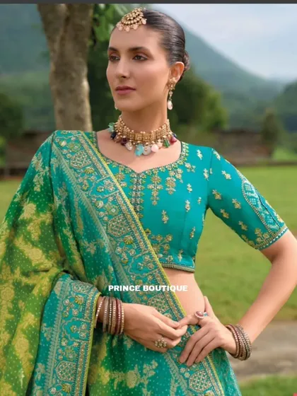 A close-up of the teal and green lehenga, focusing on the beautifully embroidered blouse and the contrasting bandhani-style dupatta.