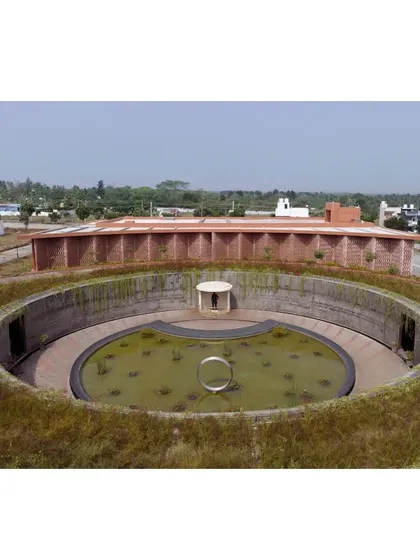 A wider aerial view showing the memorial's placement within the larger context of Mysore's outskirts, designed to blend with the rural setting.