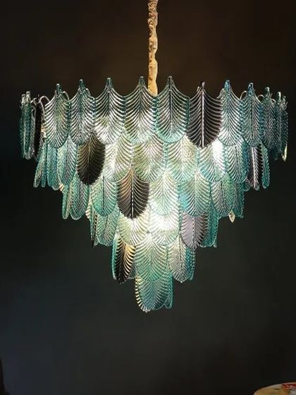 A masterpiece of cascading glass leaves. This chandelier creates a stunning visual effect, with layers of teal-colored glass that beautifully filter the light, adding grandeur and artistry to any space.
