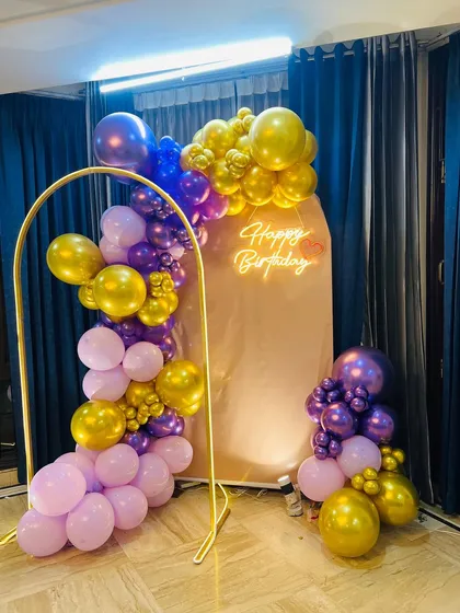Another perspective of the purple and gold balloon arch, showing the full arrangement for an indoor home celebration.