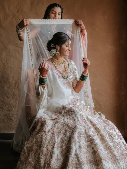 The final veil placement for the bride. Her makeup is soft and romantic, with a focus on glowing skin and defined eyes.