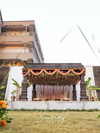 A distant shot of the temple-style mandap, framed by vibrant marigold arrangements, highlighting the scale of the event.