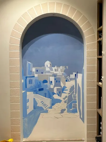 The Santorini mural in progress, with the architectural forms of the village blocked in. This behind-the-scenes shot shows the careful layering of blues and whites to create depth and shadow.