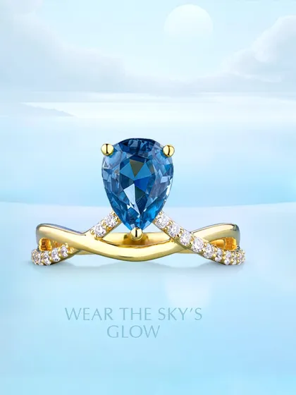 Wear the sky’s glow. This custom ring showcases a radiant pear-shaped blue topaz set on a twisted, diamond-accented gold band. It is designed to bring both elegance and a personal touch to your collection.