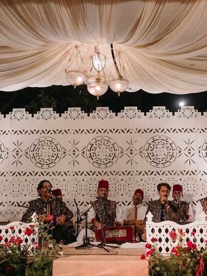 The stage setup for the Sufi night, featuring a white-on-white design with a patterned backdrop, draped ceiling, and vintage-style glass lanterns.