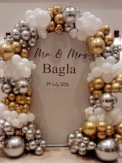 Congratulations to the happy couple. We designed this elegant and modern backdrop for Mr. & Mrs. Bagla's anniversary, featuring a beautiful balloon arch in chrome silver, gold, and white, framing a personalized sign with their names and special date.