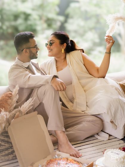 A sweet, conversational moment during a cozy indoor pre-wedding shoot. The image captures the easy comfort and communication between the couple, making it feel natural and real.