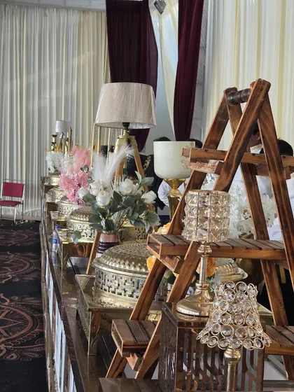 Our wedding buffet setups are a blend of function and artistry. This display features a rustic wooden ladder shelf for serving ware, crystal candle holders, and elegant floral arrangements, adding a decorative touch to the food service.