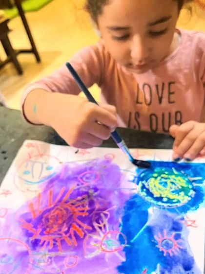 A student discovers the joy of layering watercolors over her crayon drawings. The results are always a beautiful surprise.