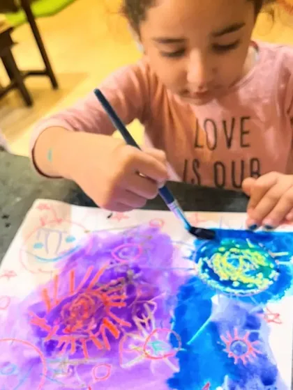 A student discovers the joy of layering watercolors over her crayon drawings. The results are always a beautiful surprise.