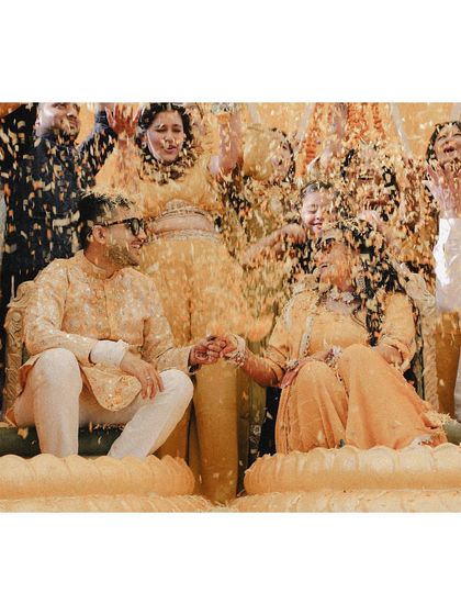 A beautiful shot of the couple holding hands while being showered with a cascade of flower petals.