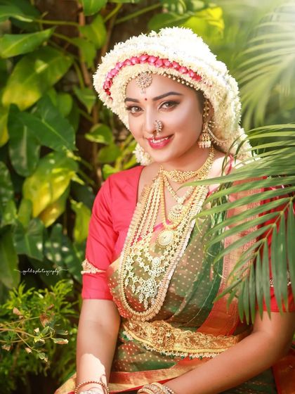 The sunlight filtering through the leaves creates a beautiful, natural glow in this portrait, highlighting the bride's radiant smile.