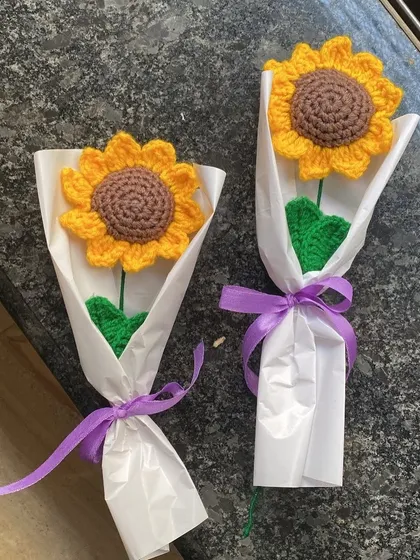Two single sunflowers, each wrapped simply in white paper with a purple ribbon. They make a perfect pair of small gifts.