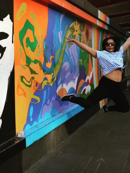 A joyful leap in front of a vibrant mural. I believe dance should be fun and expressive, and I always look for ways to bring that sense of playfulness into my choreography sessions.