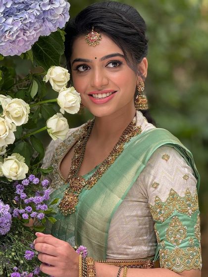 A lovely candid moment of the bride with a bouquet of flowers. The makeup is soft and natural, enhancing her beauty.