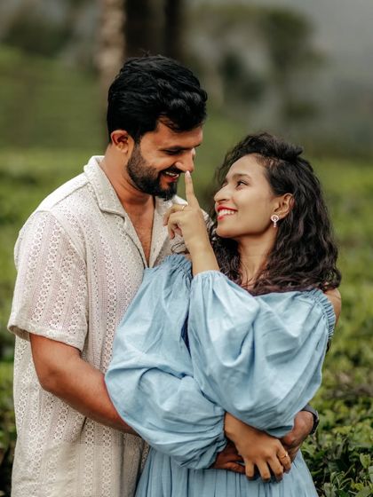 A playful and intimate moment between a couple in a tea garden, their smiles lighting up the frame.