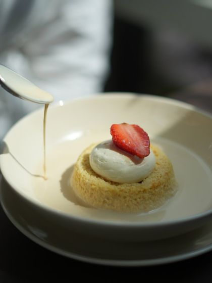 A spoonful of creamy milk sauce being poured over my Tres Leches cake, enhancing its moistness and flavor.