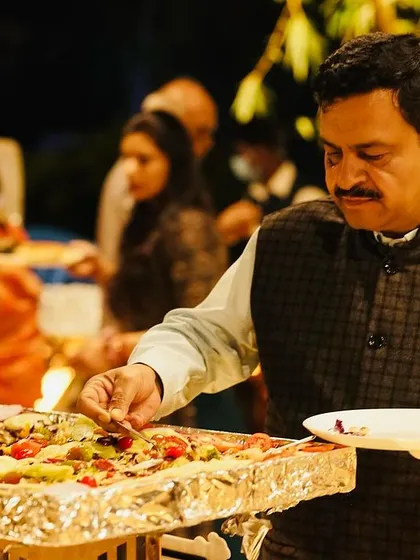 A guest helping himself to a large platter of fusion pizza at an event. My interactive and large-format dishes encourage guests to mingle and enjoy the food together.