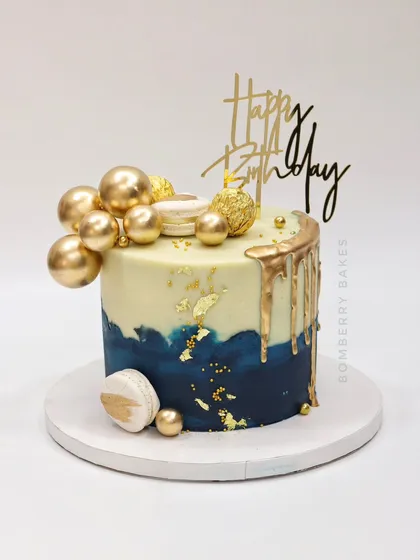 A stylish blue and gold drip cake with a "Happy Birthday" topper, perfect for any celebration.