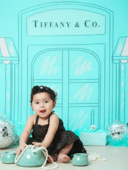 For a touch of glamour, we offer creative themes like this 'Breakfast at Tiffany's' inspired shoot, complete with a custom backdrop and props for a unique baby portrait.