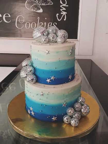 A cool and groovy disco-themed cake. This two-tiered design has a blue ombre effect and is decorated with silver stars and sparkling disco balls.