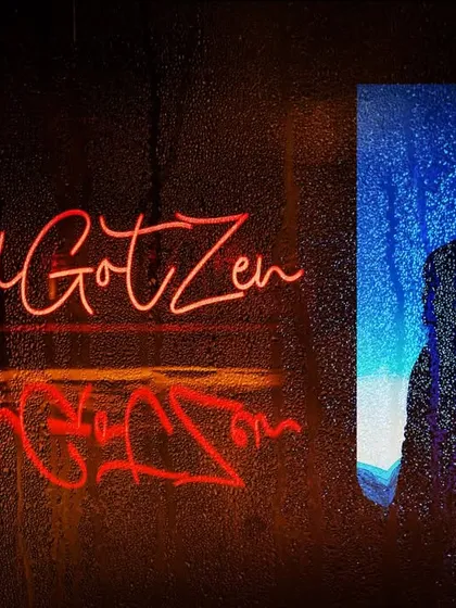 A creative monsoon-themed engagement portrait. The couple's silhouette is seen through a rain-streaked surface, with their neon hashtag reflected, creating a moody and romantic vibe.