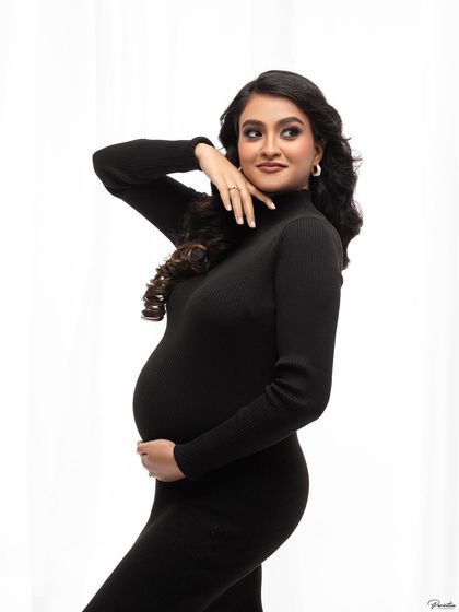 A classic and elegant pose in the black turtleneck dress, looking off-camera with a gentle smile. Timeless and sophisticated.