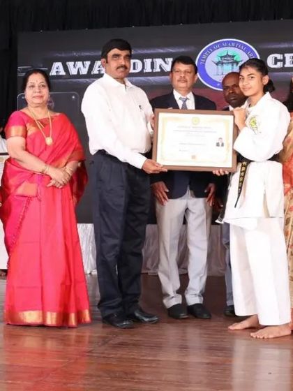 A female black belt recipient with her family and instructors. We celebrate these achievements as a community, honoring the dedication of both the student and their support system.