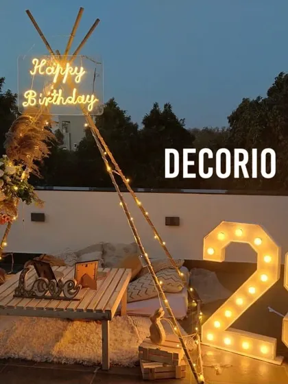 A cozy and romantic teepee setup on a terrace for a 29th birthday. This intimate arrangement includes a 'Happy Birthday' neon sign, large marquee numbers, fairy lights, and comfortable seating, creating a perfect atmosphere for a relaxed celebration.