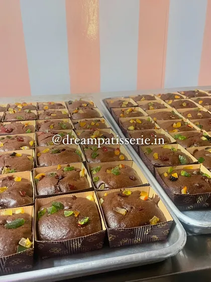Freshly baked plum cakes, studded with colorful candied fruits, cooling on trays. This is part of the large-scale production for our Christmas corporate gift hampers.