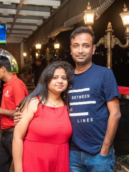 A couple enjoying their evening with a live cricket match visible on the screen behind them. My pub is designed so you can enjoy a conversation and still keep an eye on the score.