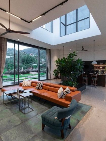 A modern wooden staircase set against a large window, making the journey between floors an experience with nature. The vertical wooden slats act as a screen, adding texture and a sense of privacy.