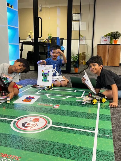 Here is where the magic begins. Our young 'Roboteers' are seen here collaborating and preparing their custom-built robots for a soccer competition, learning teamwork, design, and mechanics in a fun, hands-on environment.