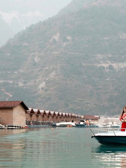 A wide-angle shot capturing the scale and beauty of the Tehri Lake location, with the couple enjoying a private boat ride for their pre-wedding shoot.