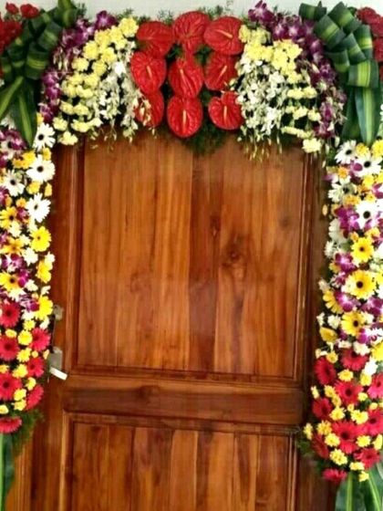 A housewarming flower decoration for a flat. The door is adorned with an arch of colorful fresh flowers including anthuriums and gerberas.