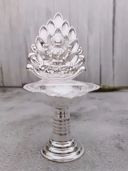 A German silver diya with a lotus-shaped backplate featuring Goddess Lakshmi, combining two auspicious symbols in one.