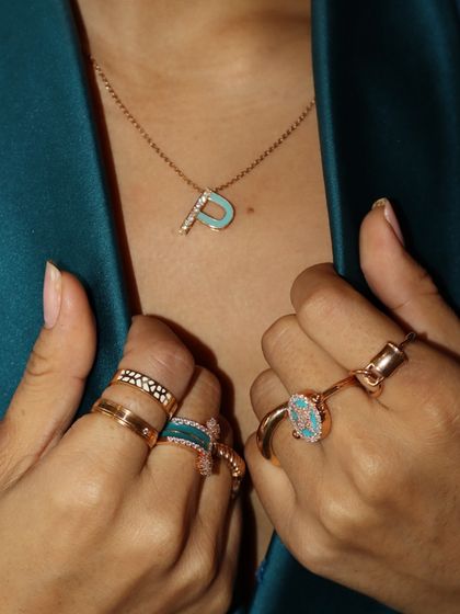 Your initials, your vibe. This customizable 'P' initial pendant is crafted with turquoise-colored enamel and diamonds, shown here layered with a curated stack of enamel and gold rings.