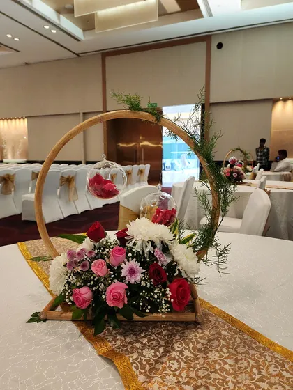 A variation of our popular hoop centerpiece, this time with pink, red, and white flowers. The hanging glass orbs contain small red flowers, tying the whole arrangement together.